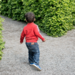 Jongentje met ADHD loopt op een tuinpad.