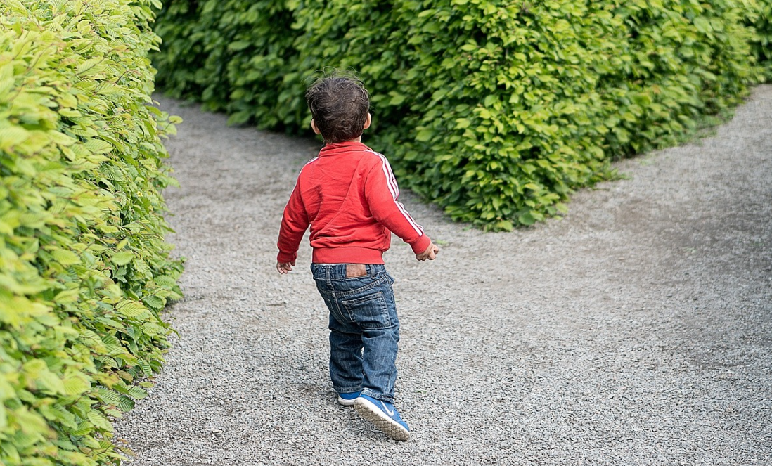 Jongentje met ADHD loopt op een tuinpad.