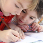 Een meisje en jongen met ADHD en autisme zijn aan het tekenen op school in de klas.