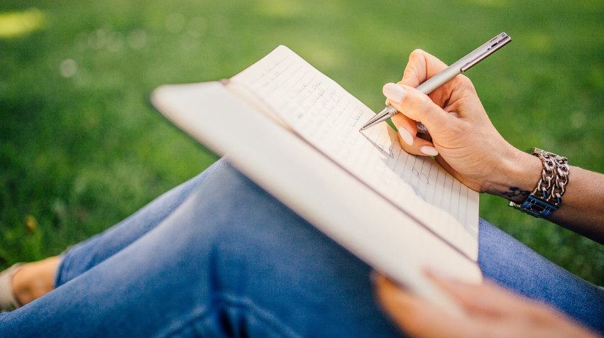 Vrouw schrijft haar gedachten op in een schrift.